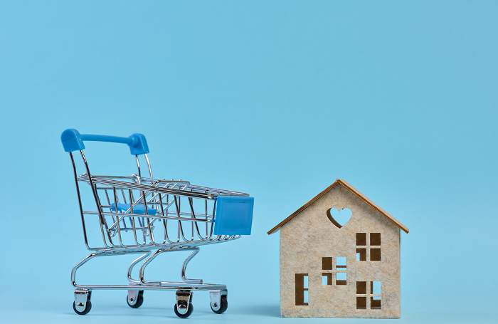 Wooden house and miniature shopping cart, representing the concept of real estate purchase, rental growth, and mortgage interest Wooden house and miniature shopping cart, representing the concept of real estate purchase, rental growth, and mortgage interest