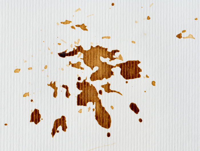 Spilled black coffee on white paper background, drops Spilled black coffee on white paper background, drops
