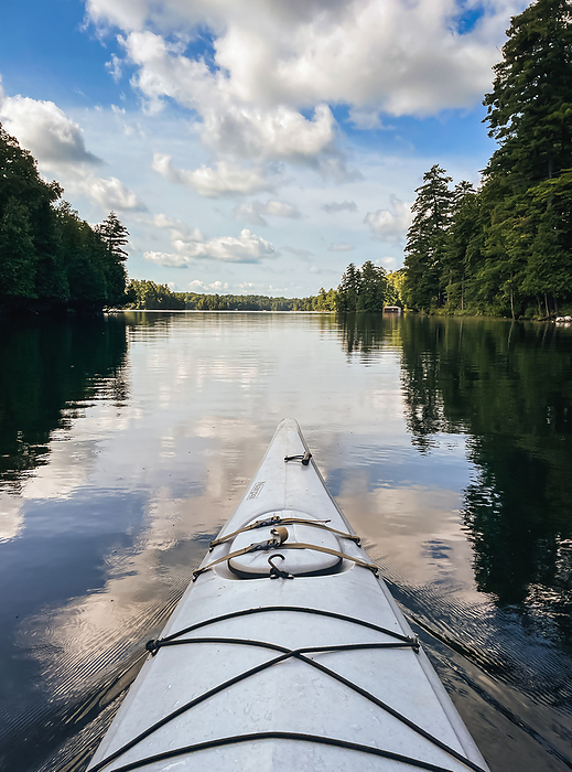 View of calm lake and front of kayak from paddler perspective., by Cavan Images / Dorene Hookey