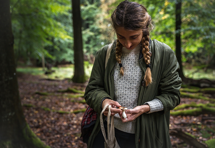 Woman With Long Braids Identifying Mushrooms In Scandinavia, by Cavan Images / Emily Wilson Photography