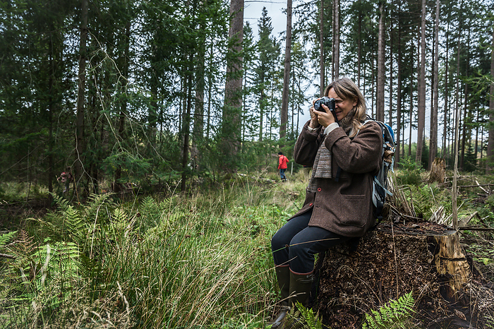Photographer Sitting In The Forest Shooting Photos In Denmark, by Cavan Images / Emily Wilson Photography
