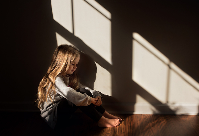 Young girl sitting quietly in beautiful light, by Cavan Images / Joy Faith