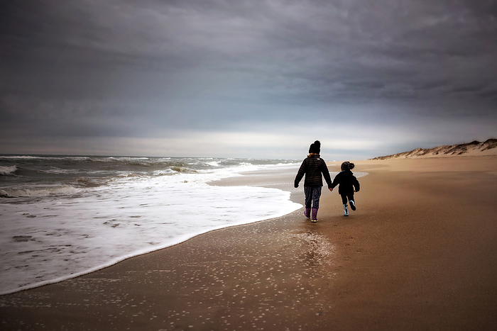 Young sisters running down the beach holding hands, by Cavan Images / Joy Faith