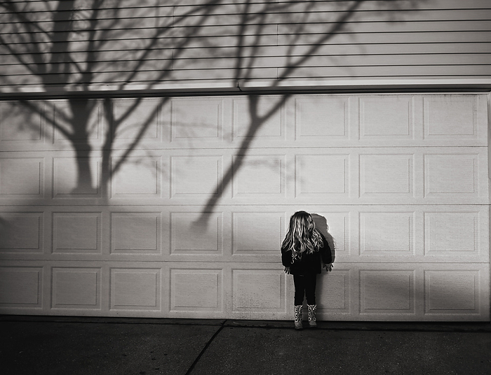 Small girl standing in creepy shadow in autumn, by Cavan Images / Joy Faith