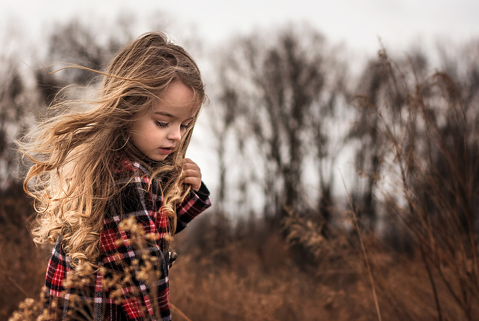 Little girl with long curly hair blowing in the wind, by Cavan Images / Joy Faith