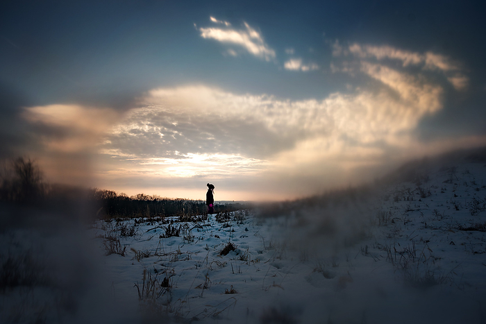 Young girl climbing snow covered hill at sunset, by Cavan Images / Joy Faith