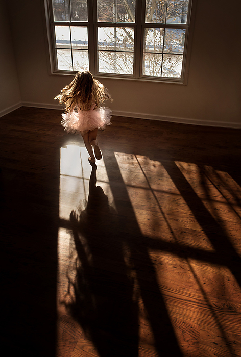 Little girl with long curls dancing and spinning in pink tu tu, by Cavan Images / Joy Faith