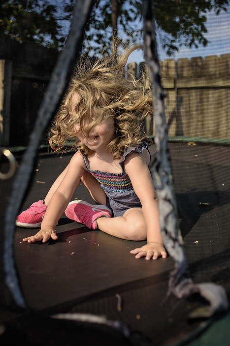 Little girl jumping on trampoline in summer, by Cavan Images / Joy Faith
