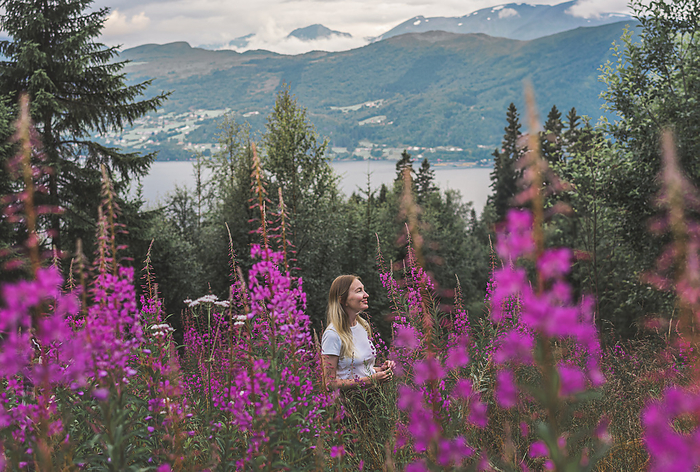 woman in the mountains among the flowers of fireweed in Norway, by Cavan Images / Anastasiia Akh