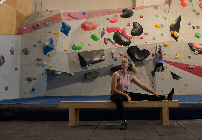 Woman stretching getting ready to climb indoors with her daughter, by Cavan Images / Rachel Bell