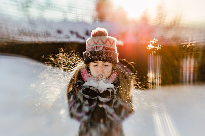 girl blowing snow during winter at sunset, by Cavan Images / Annick Paradis