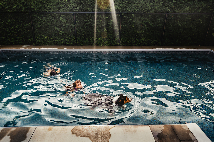 dog swimming in the pool with a boy and a girl at his suite, by Cavan Images / Annick Paradis