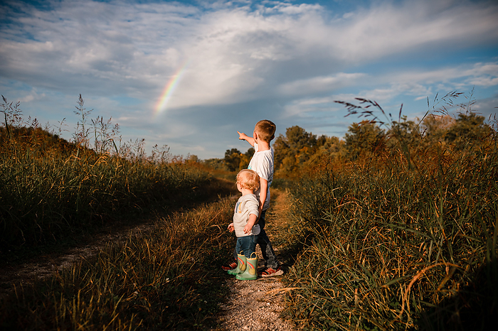 Brother pointing out rainbow to sister on autumn day on scenic c, by Cavan Images / Krista Taylor