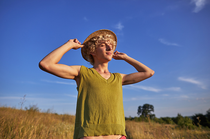 happy young man closing his eyes from the bright sun, by Cavan Images / Elena Perevalova