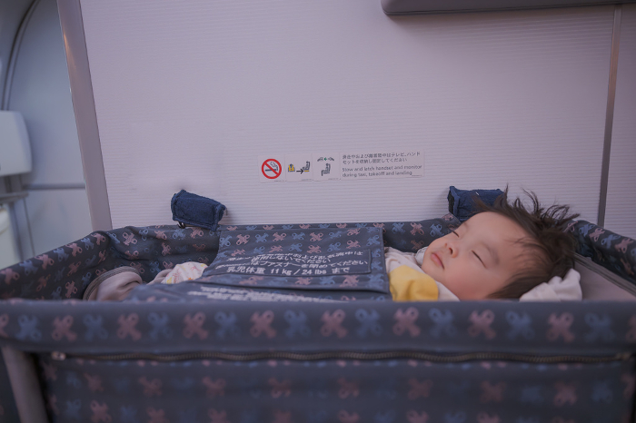 Baby sleeping in bassinet on airplane