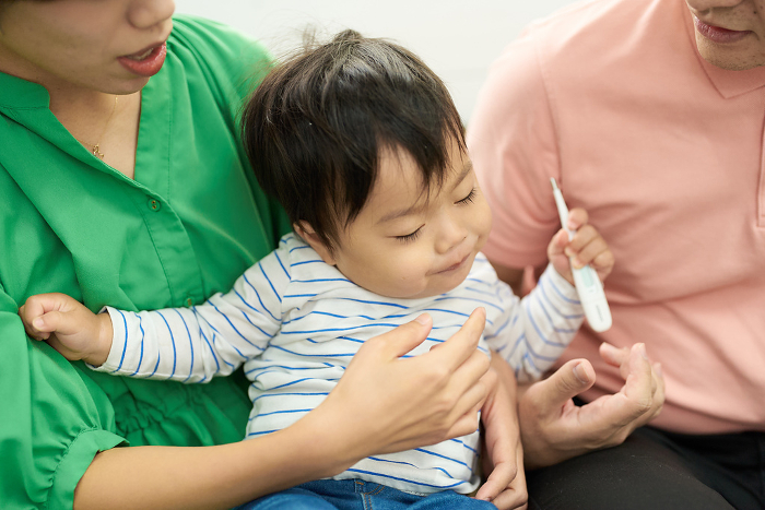 Japanese boy having his temperature measured by his parents (People)