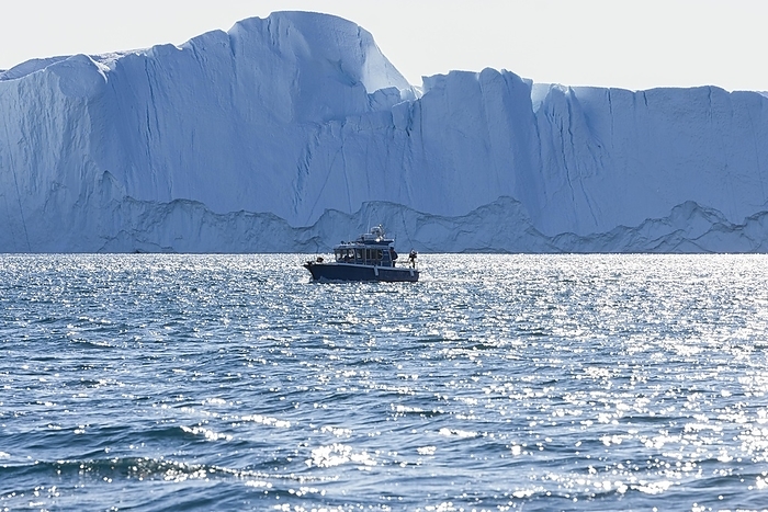 Ilulissat Icefjord A small excursion boat sails in front of a huge iceberg in the UNESCO World Heritage Ilulissat Icefjord. Disko Bay, Greenland, Denmark, North America