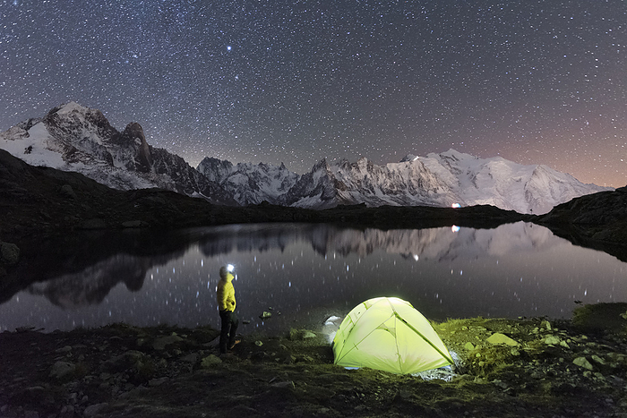 Person admiring the starry sky outside tent pitched on the shore of Cheserys lake surrounded by alpine landscape of Mont Blanc, Chamonix, Haute Savoie, French Alps, France, Europe Person admiring the starry sky outside tent pitched on the shore of Cheserys lake surrounded by alpine landscape of Mont Blanc, Chamonix, Haute Savoie, French Alps, France, Europe, by Paolo Graziosi