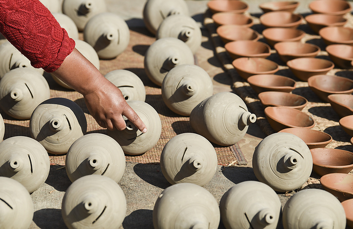 A craftswoman shows off the traditional clay pots she left to dry in the sun, Bhaktapur, Nepal, Asia A craftswoman shows off the traditional clay pots she left to dry in the sun, Bhaktapur, Nepal, Asia, by Mihai Coman