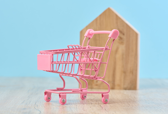 Wooden house and miniature shopping cart, representing the concept of real estate purchase, rental growth, and mortgage interest Wooden house and miniature shopping cart, representing the concept of real estate purchase, rental growth, and mortgage interest