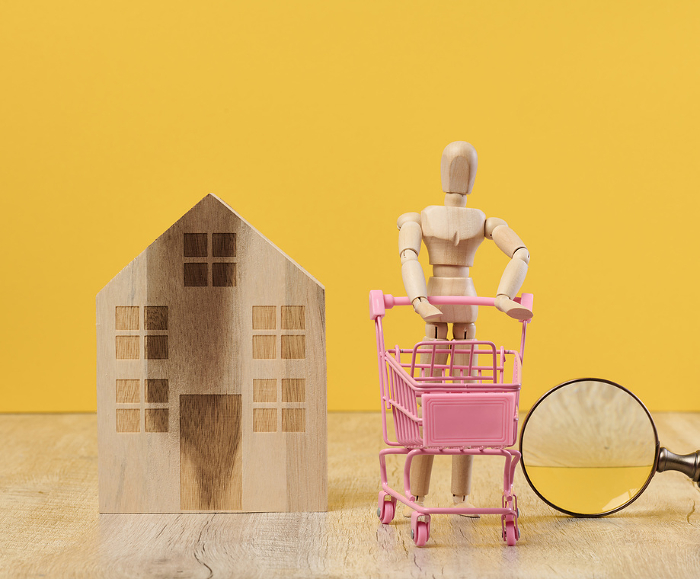 Wooden house and miniature figurines on a yellow background. The concept of selling and buying real estate, investment Wooden house and miniature figurines on a yellow background. The concept of selling and buying real estate, investment