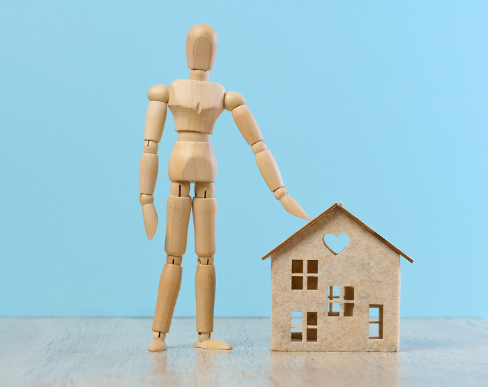 Wooden dummy, house, representing the concept of real estate purchase, rental growth, and mortgage interest Wooden dummy, house, representing the concept of real estate purchase, rental growth, and mortgage interest