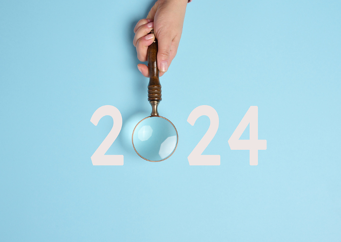 A female hand holds a magnifying glass and the inscription 2024, symbolizing the arrival of the new yea A female hand holds a magnifying glass and the inscription 2024, symbolizing the arrival of the new yea
