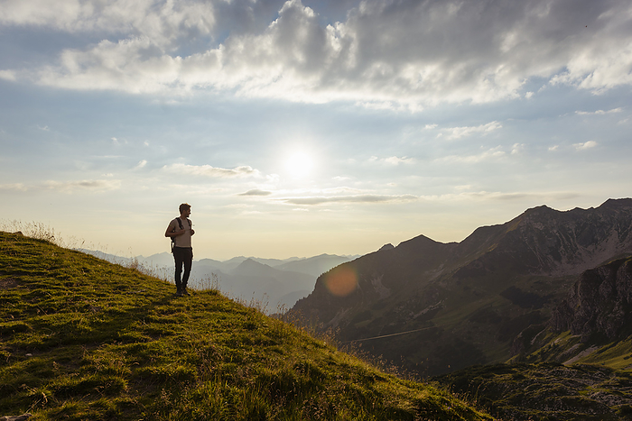 Germany, Bavaria, Oberstdorf, man on a hike in the mountains looking at view at sunset