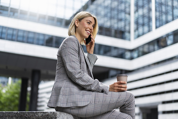 Happy young businesswoman on the phone in the city
