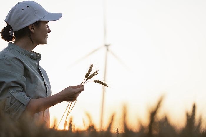 Farmer wearing hat holding wheat crops in field