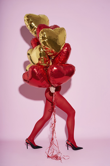 Women s legs in red tights with balls in their hands. Women wearing stocking holding balloons