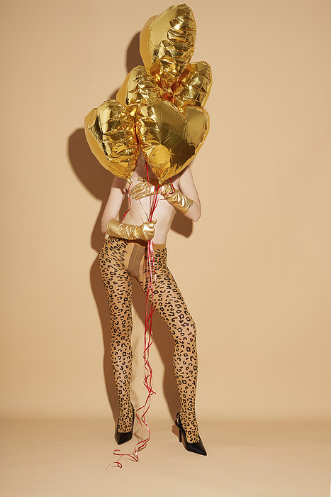 Woman in leopard tights with golden balloons Shirtless woman wearing stocking and holding golden colored balloons