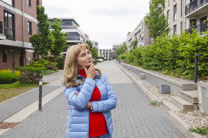 Contemplative woman standing near residential area