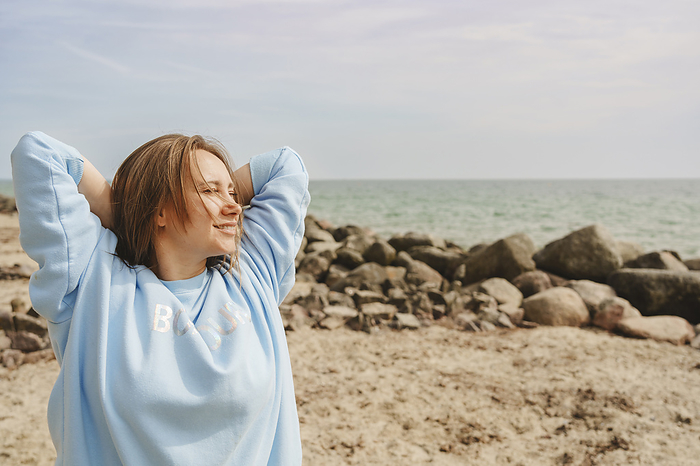 Smiling woman with eyes closed standing at beach