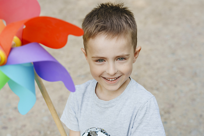 Smiling boy with colorful rainbow pinwheel toy