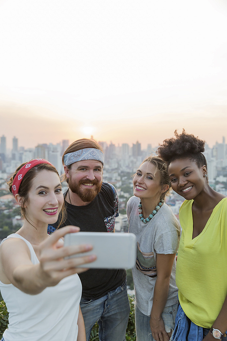 Woman taking selfie with friends in front of sunset sky