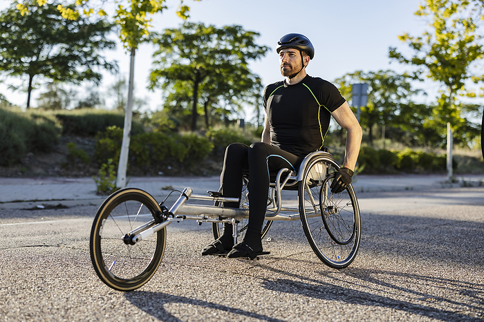 Sportsman sitting in wheelchair on road