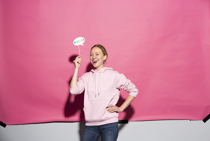 Studio Line Happy woman with prop and hand on hip over pink background