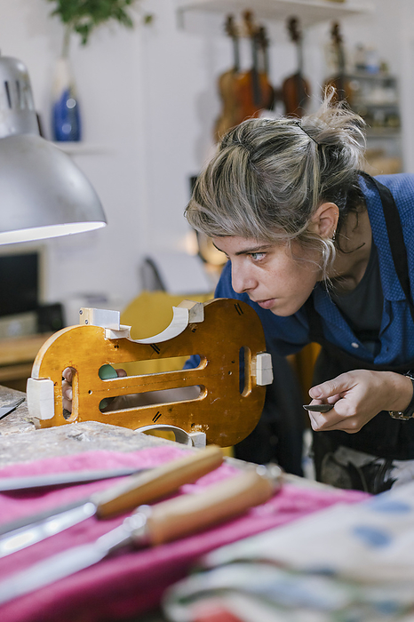 Young luthier working at her workshop Luthier working on violin in musical instrument workshop