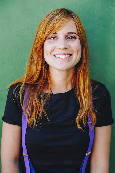 Smiling redhead woman in front of green wall