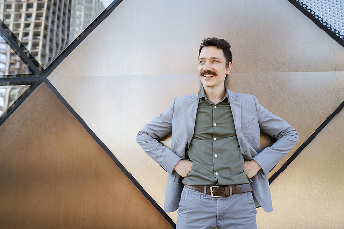 Smiling businessman with mustache standing in front of modern office building