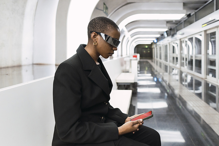 Young woman wearing smart glasses and using smart phone at metro station