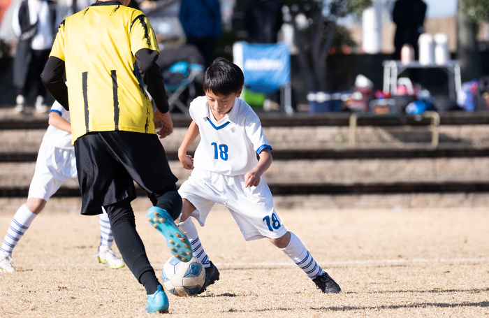 An elementary school boy playing a soccer game