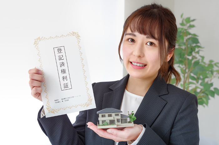Woman with real estate title and house model