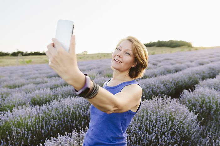Smiling woman taking selfie amidst lavender field