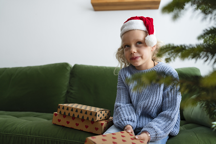 Thoughtful girl sitting with Christmas presents at home