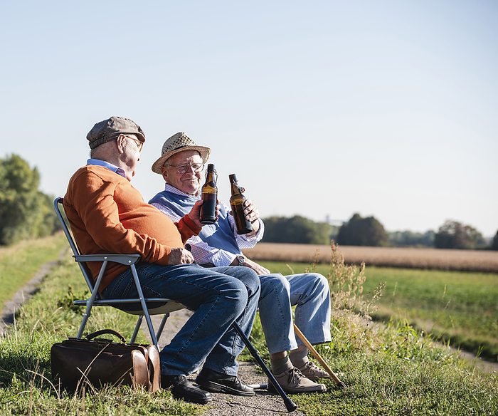 Two old friends sitting in the fields, drinking beer, talking about old times