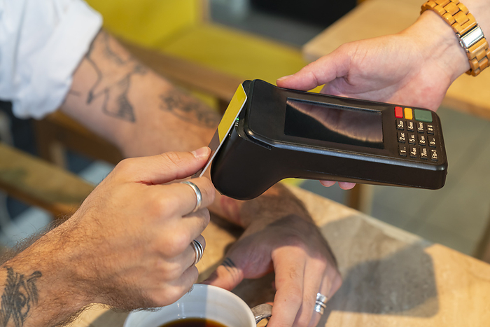 Man paying via tap to pay at cafe