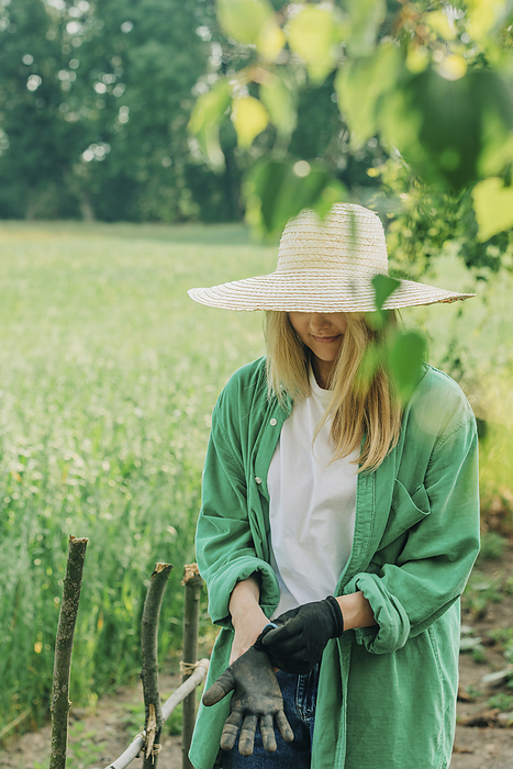 Woman with hat wearing gloves in garden