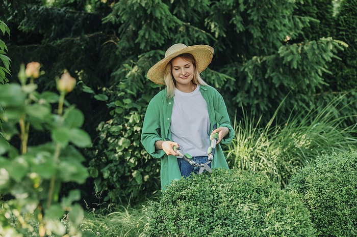 Smiling woman cutting plants in garden